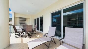 A balcony with a dining table and chairs, a sliding glass door, and a view of a building.