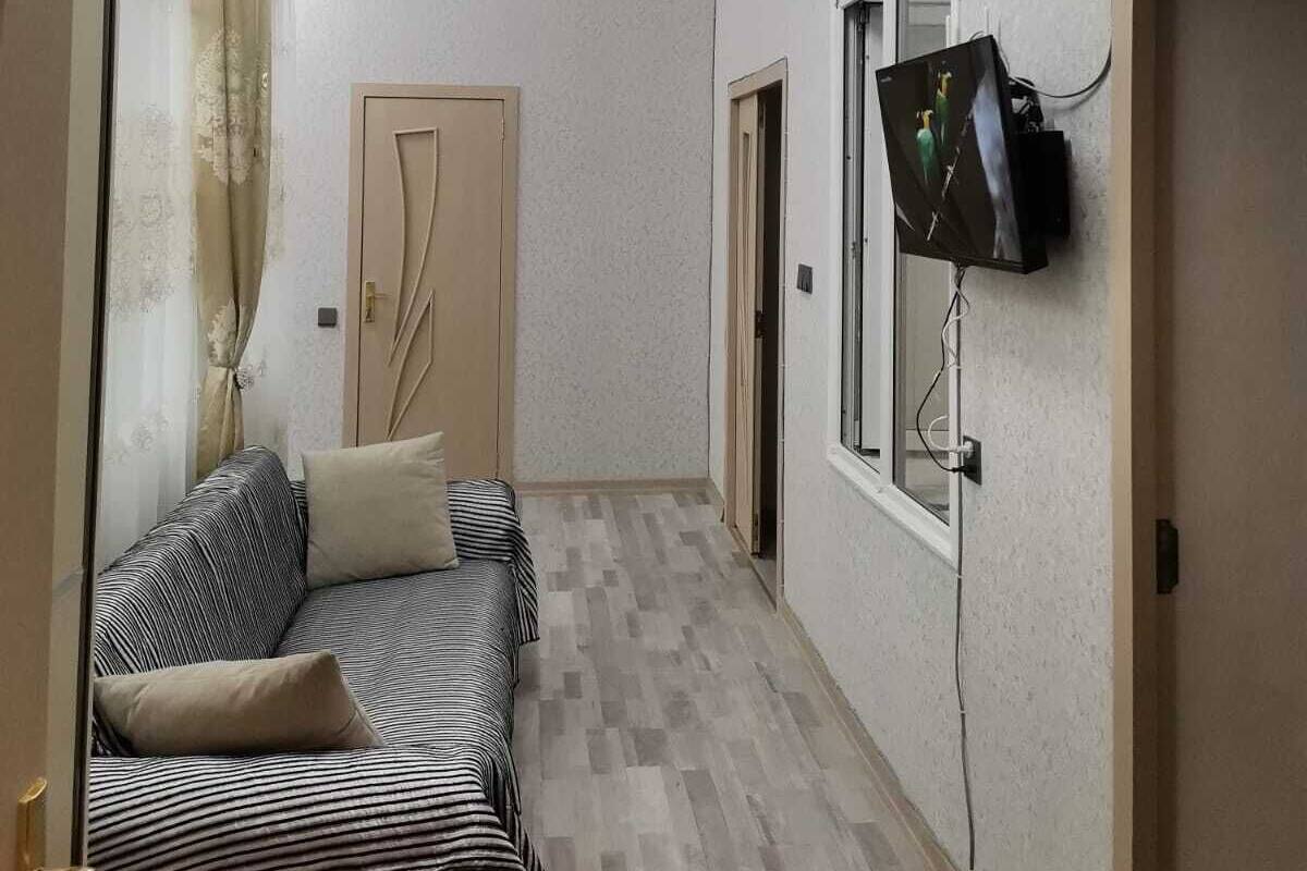 Een gang met een bank, een televisie aan de muur en een deur aan het einde.