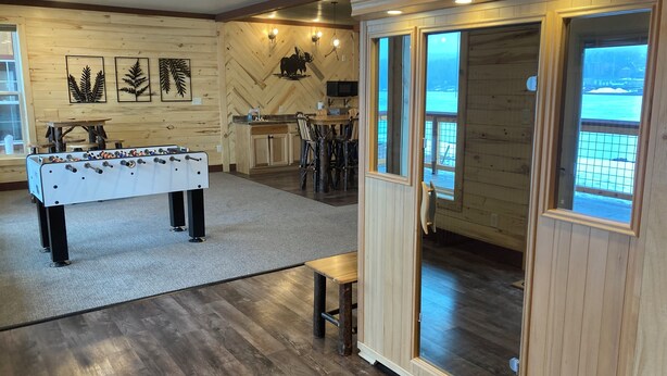 Una habitación acogedora con mesa de fútbol de mesa, paredes de madera y un amplio ventanal con vistas a un paisaje nevado.
