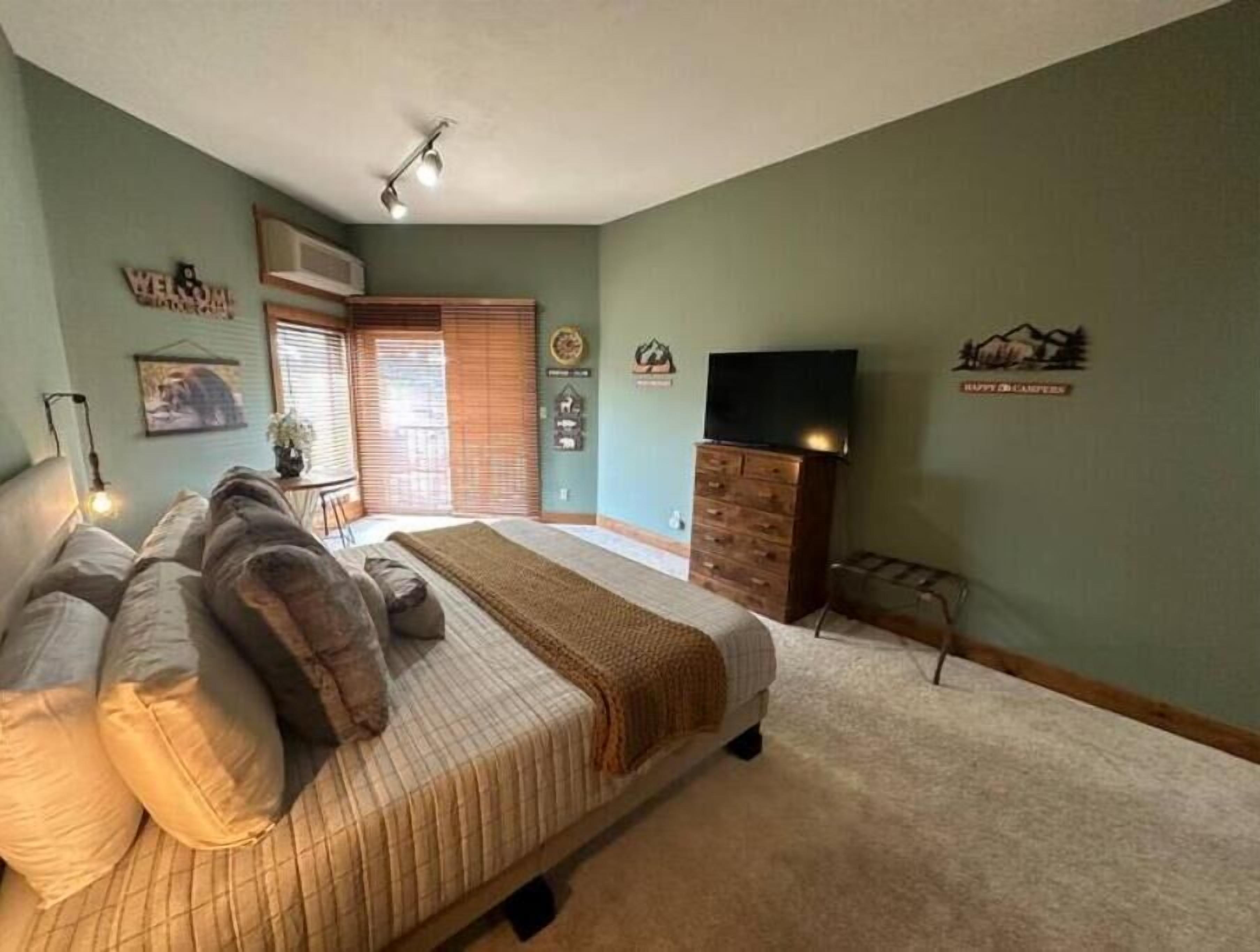 Une chambre à coucher avec un lit, une commode et un téléviseur.