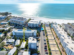 An aerial view of a coastal hotel area with multiple buildings, a parking lot, and a beach in the background. - Hidden Paradise by Beachside Management (Siesta Key)