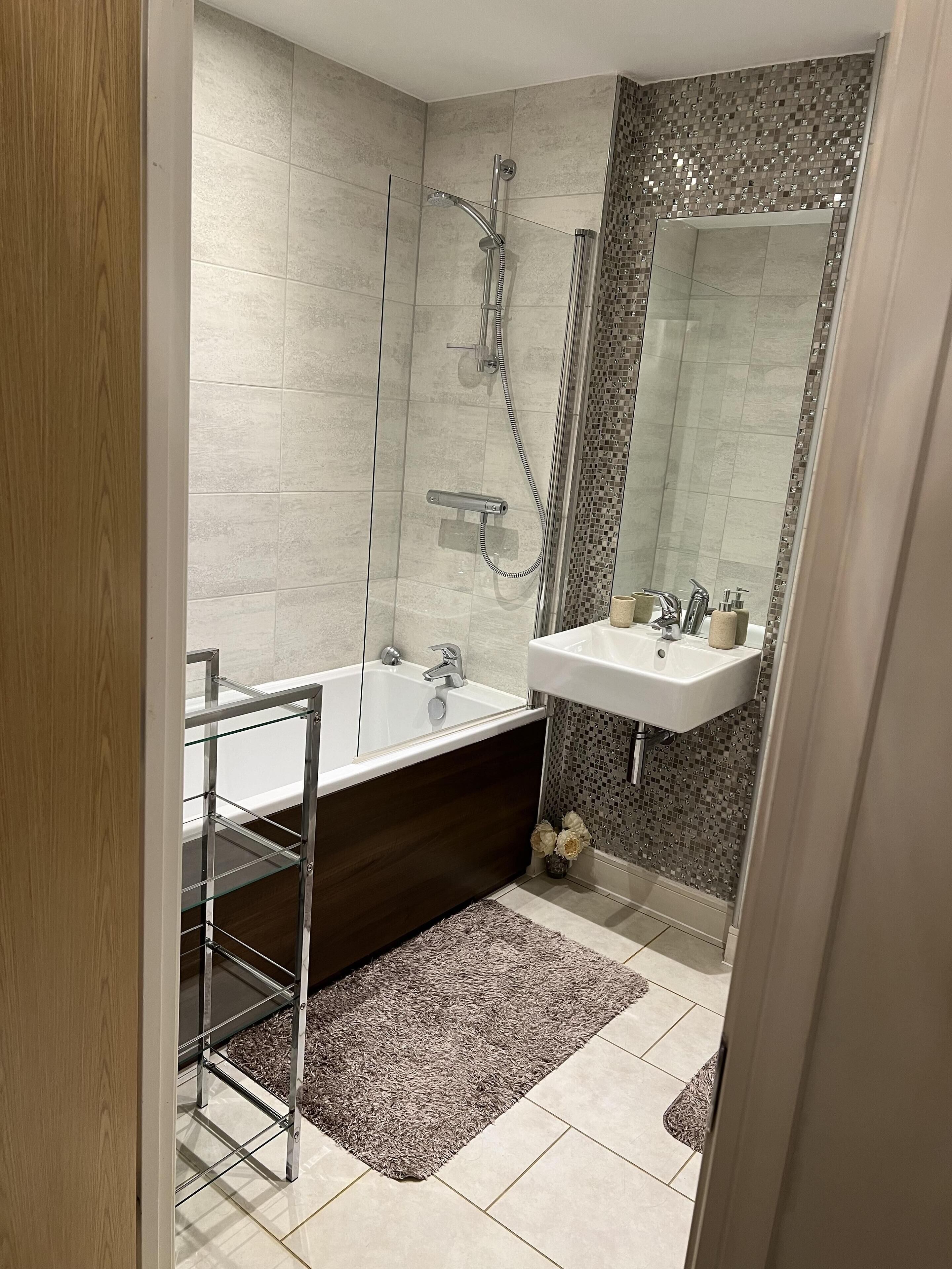 A modern bathroom with a glass-enclosed shower, a freestanding bathtub, and a vanity with a mirror.