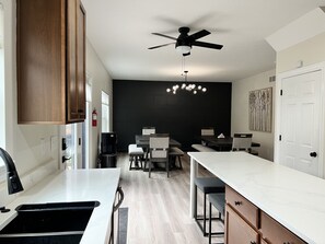 A modern kitchen with a central island, a ceiling fan, and a dining area with a dark accent wall.