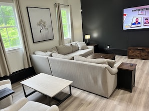 A modern living room with a sectional sofa, a coffee table, and a TV mounted on the wall.