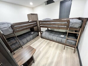 A bunk bed room with a wooden desk and a wardrobe.
