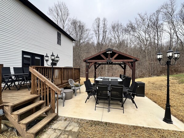 A patio with a wooden deck, outdoor seating, and a hot tub.