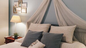 A bedroom with a canopy bed, a bedside table with a lamp, and framed pictures on the wall. - Monastiraki Psiri, 1-bedrom apartment, sleep 2-4p, Old Town, Great Court Yard. (Athina)