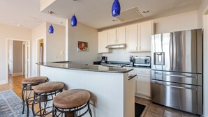 Una cocina moderna con una isla central, electrodomésticos de acero inoxidable e iluminación colgante.