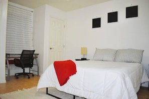 A bedroom with a bed, a desk, and a chair.