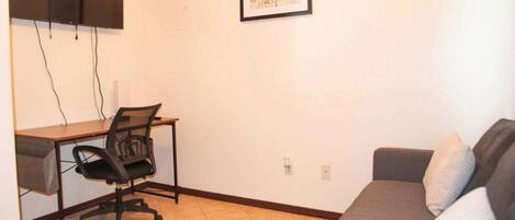 A small, furnished room with a desk, chair, and a couch.