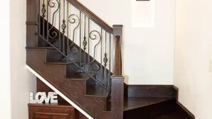 Un escalier en bois, doté d’une finition sombre et de balustres décoratives.