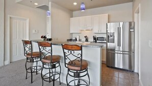 A modern kitchen with a central island, stainless steel appliances, and bar stools. - Beautiful Downtown Condo "Unbeatable Location" with Secure Onsite Parking (New Orleans)