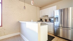 A modern kitchen with white cabinets, a stainless steel refrigerator, and a built-in island.