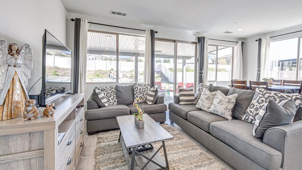 Een moderne woonkamer met grijze banken, een houten salontafel en een tv op een houten kast.