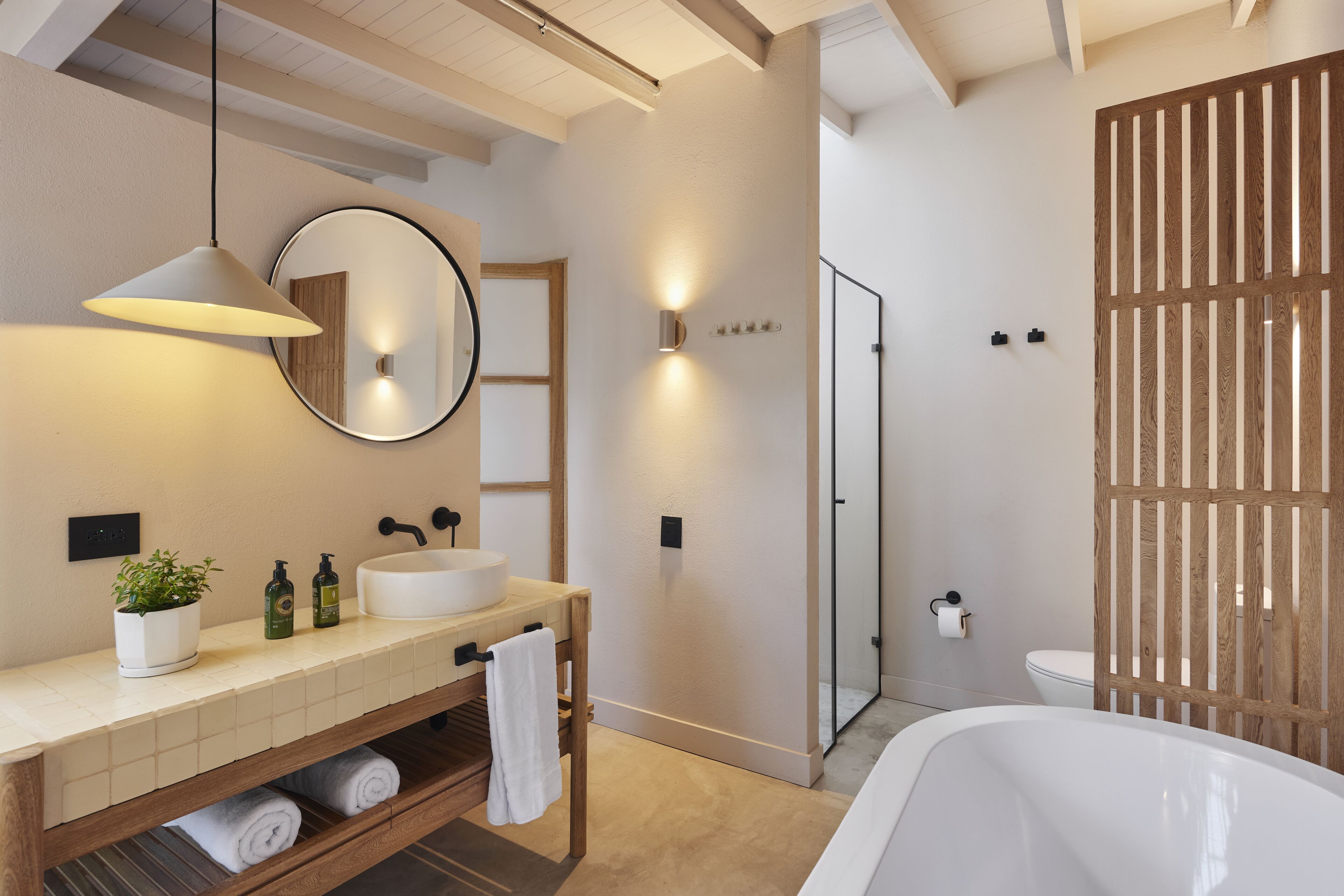 Een moderne badkamer met een houten wastafel, een grote spiegel, een rond wasbakje, een badkuip en een inloopdouche.