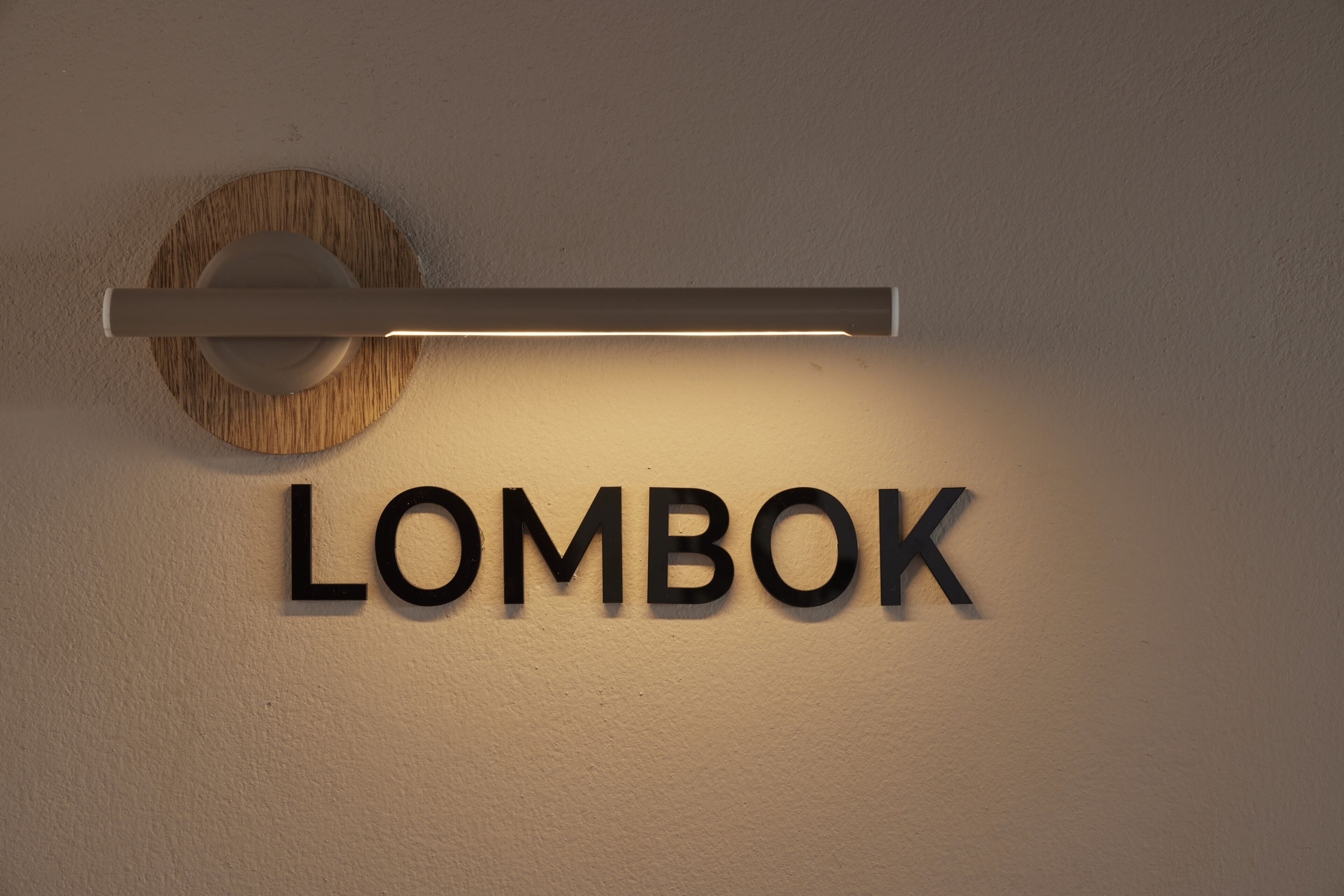 Un letrero en la pared con la palabra 'LOMBOK' en letras negritas y mayúsculas.