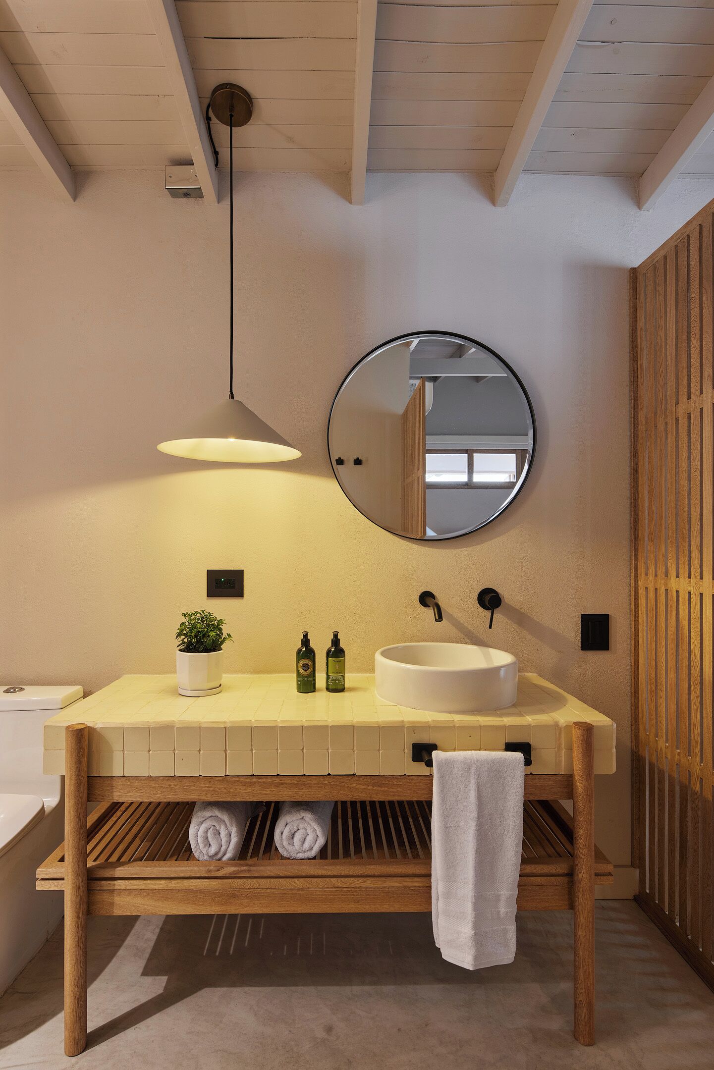 A modern bathroom with a wooden vanity, a round mirror, and a built-in sink.