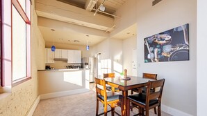 Ein Essbereich mit einem Holztisch und Stühlen, eine Küche im Hintergrund und ein Bild an der Wand.