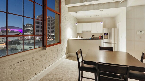 Eine moderne Küche mit weißen Schränken, einem Edelstahlkühlschrank und Blick auf die Stadt durch große Fenster.