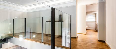 Ein modernes Interieur mit Glastrennwand, Holzboden und weißer Wand.