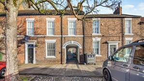 A traditional brick building with a central archway labeled "RIDLEY HOUSE APARTMENTS."