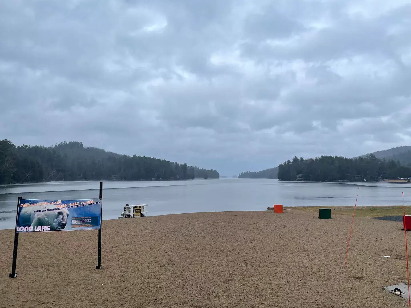 Une plage avec un panneau publicitaire annonçant un événement sur le thème des ours polaires au bord du lac Long.