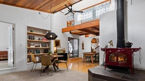 Un salon spacieux avec un haut plafond, une cheminée, un coin repas et une bibliothèque.
