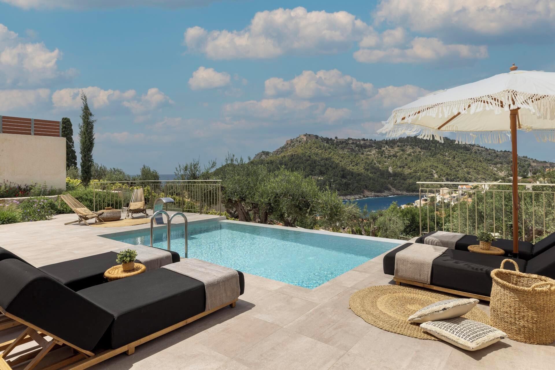 A rooftop pool area with lounge chairs, a small pool, and a view of a mountainous landscape.