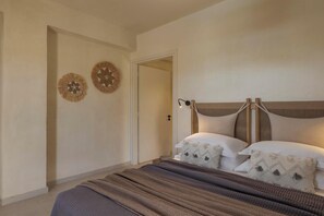 Une chambre à coucher avec un lit, deux éléments de décoration murale, une porte et une lampe de chevet.