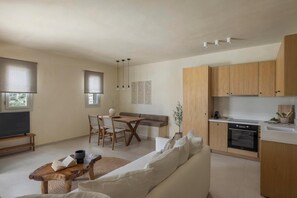 Une cuisine moderne avec des meubles en bois, un coin repas avec une table et des chaises, et un salon avec un canapé et une table basse.