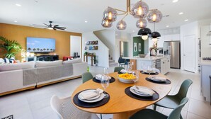 Un salon moderne avec un canapé, une table à manger dressée pour quatre personnes et une cuisine en arrière-plan.
