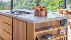 A modern kitchen with a large island, wooden cabinetry, and a view of lush greenery. - Brand-new luxury Villa Element (Provincia de Puntarenas)