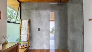 A modern bathroom with a wooden floor, a concrete shower wall, and a wooden towel rack. - Brand-new luxury Villa Element (Provincia de Puntarenas)