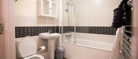 Een badkamer met toilet, wastafel en bad.