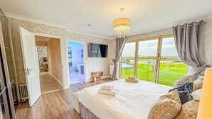 Un dormitorio espacioso con una cama grande, un candelabro y vistas a un paisaje verde.