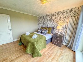 Un dormitorio ordenado con cama, mesita de noche y pared con estampado.