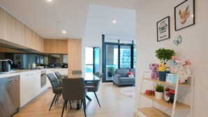 A modern apartment with a kitchen, dining area, and living room. - Pokemon Inspired Apt -Pool-Gym-Sauna-Steam Room (Adelaide)