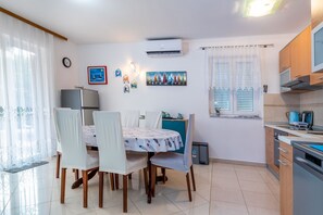 A compact kitchen with a dining area, featuring a refrigerator, stove, and dining table with chairs. - 400 metres to the famous beach (Baska)