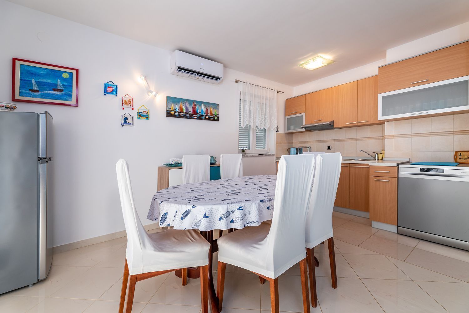 A compact kitchen with a dining area, featuring a refrigerator, microwave, and dishwasher.