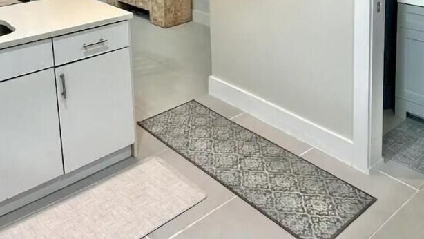 Uma cozinha moderna com armários brancos, um banco embutido e uma pintura de uma árvore na parede.