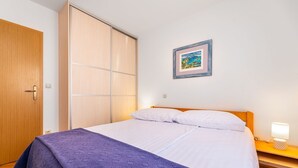 Una camera da letto con un letto, un armadio, un comodino con una lampada e un quadro appeso al muro.