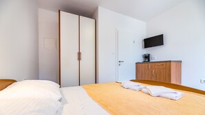 A hotel room with a bed, a wardrobe, a television, and a small kitchenette. - Only 300 metres to the fine pebble beach (Baska)