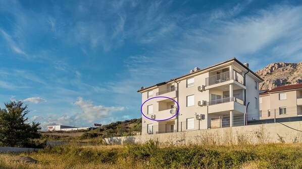 A multi-story residential building with balconies, a flat roof, and a clear sky.