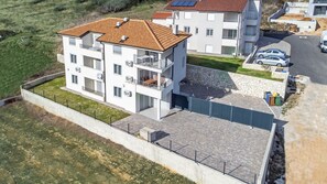 A multi-story residential building with a tiled roof, balconies, and solar panels.