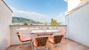 Un balcón con mesa y sillas, que ofrece vistas a un paisaje montañoso.