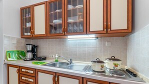 Une cuisine avec des meubles de rangement en bois, un évier, une machine à café et deux bouilloires électriques.