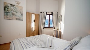 A bedroom with a bed, a wooden wardrobe, a window with curtains, and a painting on the wall. - Directly on the crystal clear Adriatic Sea (Baska)