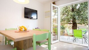 A dining area with a wooden table, green chairs, a fruit bowl, and a TV mounted on the wall. - 200 metres to the crystal clear sea (Baska)