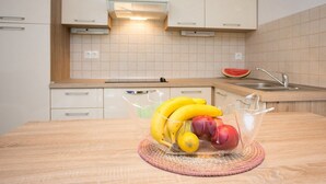 A kitchen with white cabinets, a wooden countertop, and a fruit bowl containing bananas, apples, and a lemon. - 200 metres to the crystal clear sea (Baska)