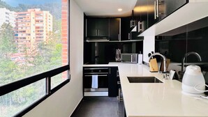 A modern kitchen with a large window, stainless steel appliances, and a view of a cityscape. - Chicala By Wynwood House (Bogotá)